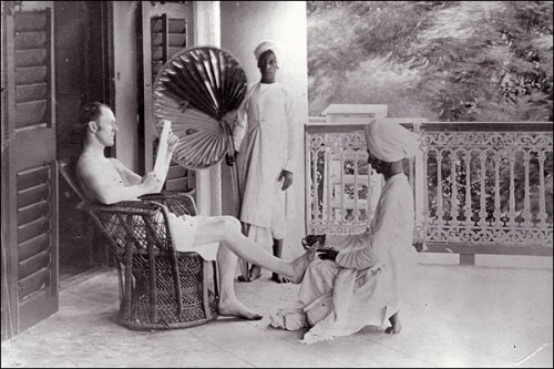 A British man gets a pedicure from an Indian servant. 